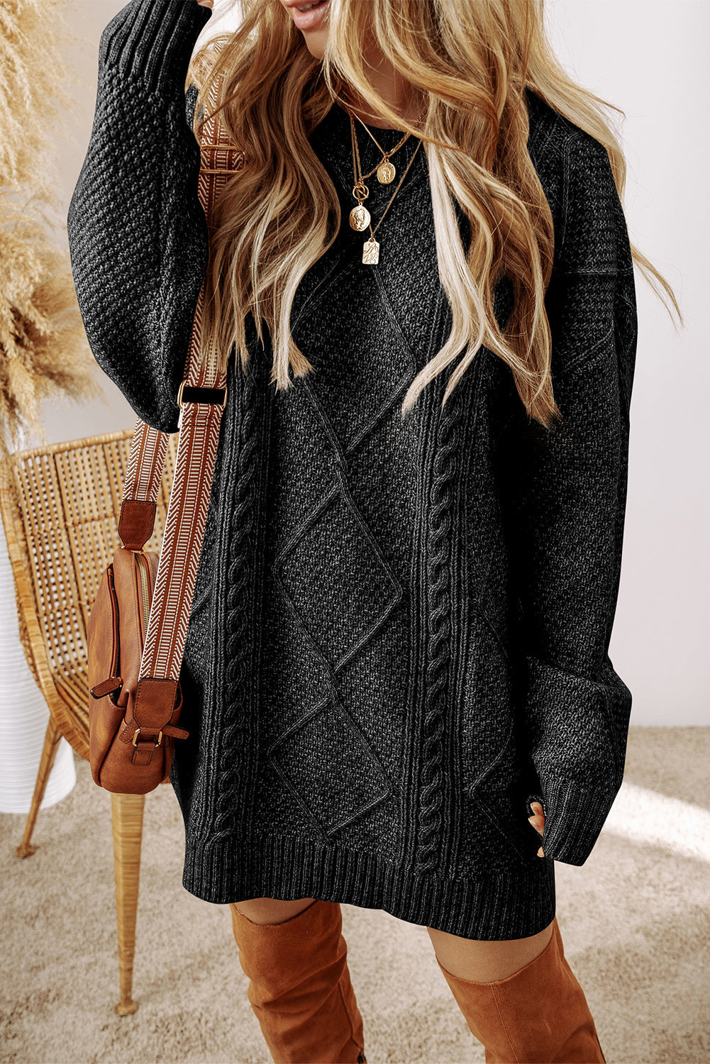 Black cable-knit sweater dress on a warm ivory boutique studio background
