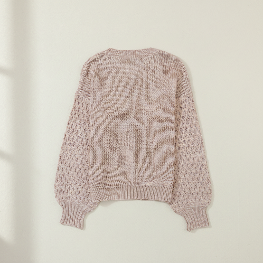 Parchment cable knit sleeve drop shoulder sweater on a warm ivory boutique studio background