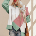 Colorblock stitching irregular hem long sleeve top on a warm ivory boutique studio background