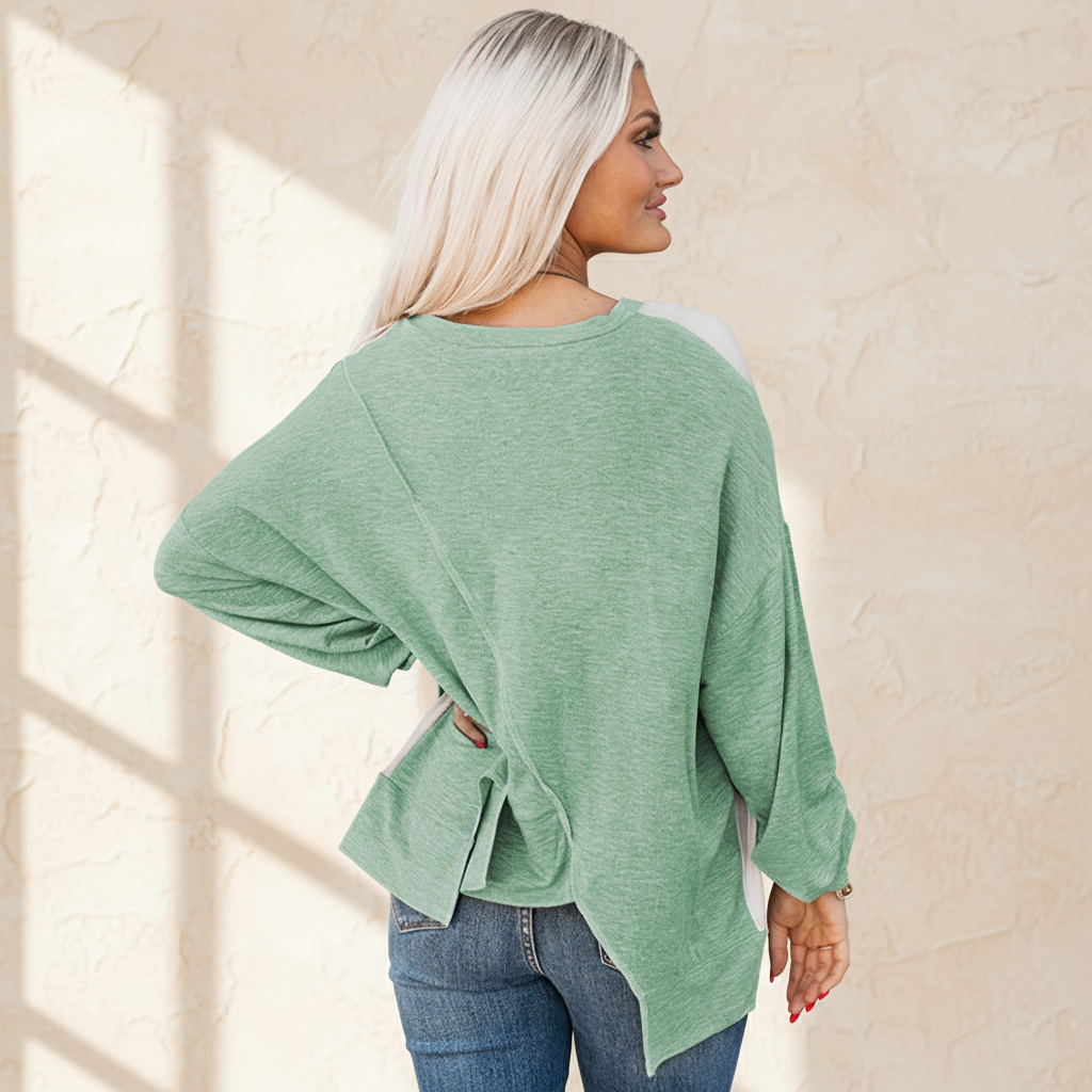 Colorblock stitching irregular hem long sleeve top on a warm ivory boutique studio background