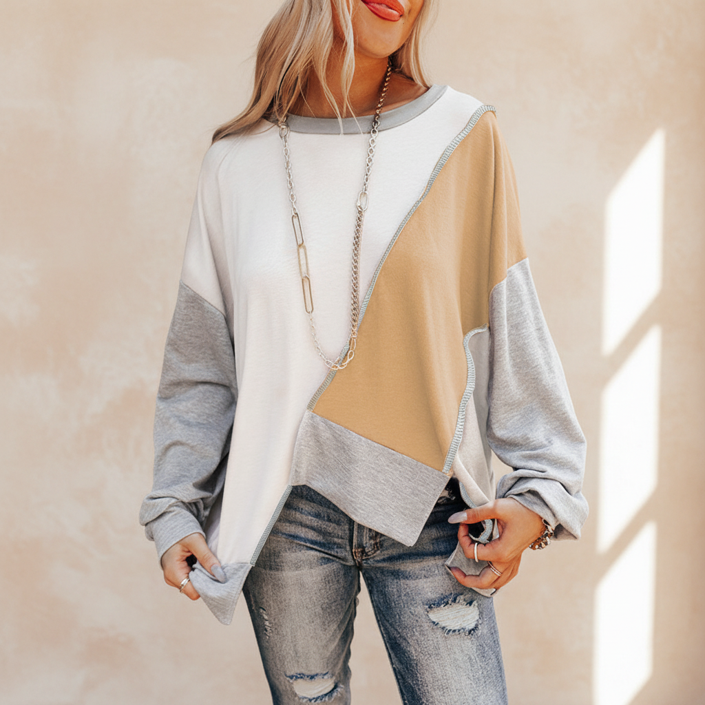 Colorblock stitching irregular hem long sleeve top on a warm ivory boutique studio background