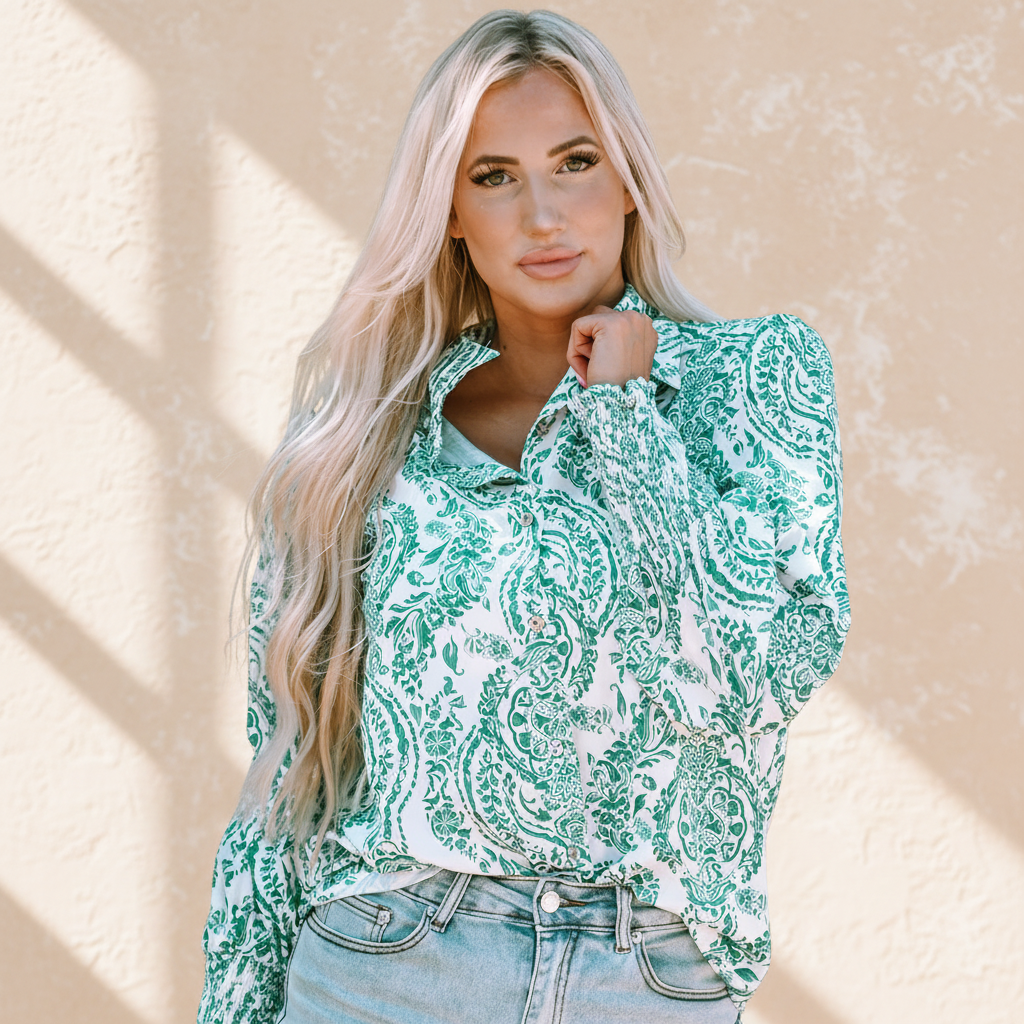 green paisley print smocked cuff buttoned loose shirt on a warm ivory boutique studio background
