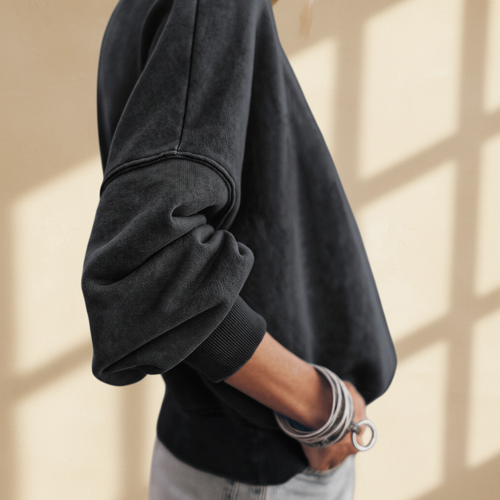 Black drop shoulder crew neck pullover sweatshirt on a warm ivory boutique studio background