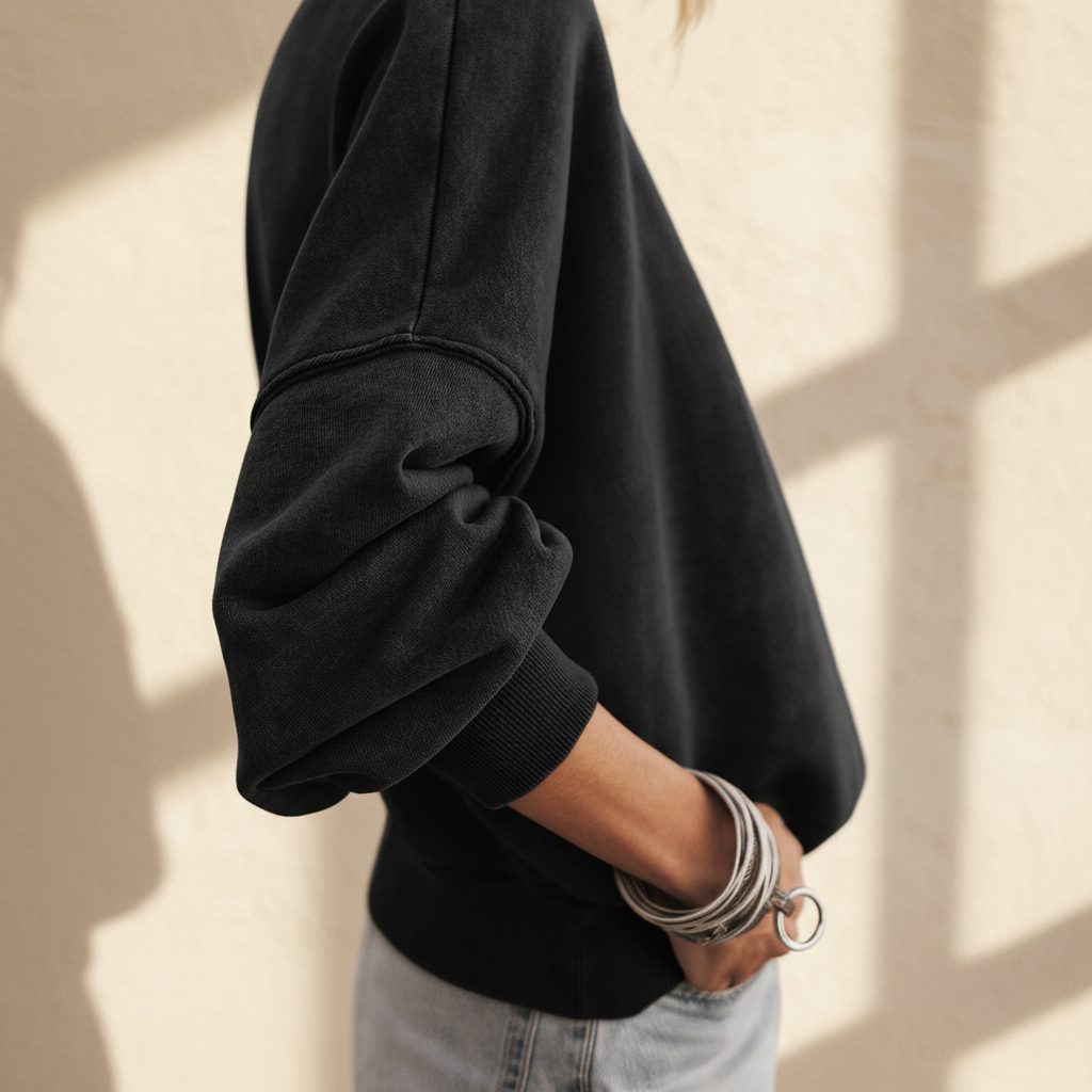 Black drop shoulder crew neck pullover sweatshirt on a warm ivory boutique studio background