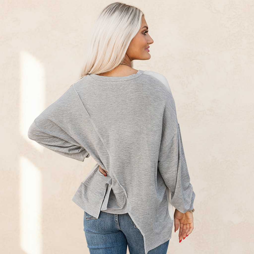 Colorblock stitching irregular hem long sleeve top on a warm ivory boutique studio background