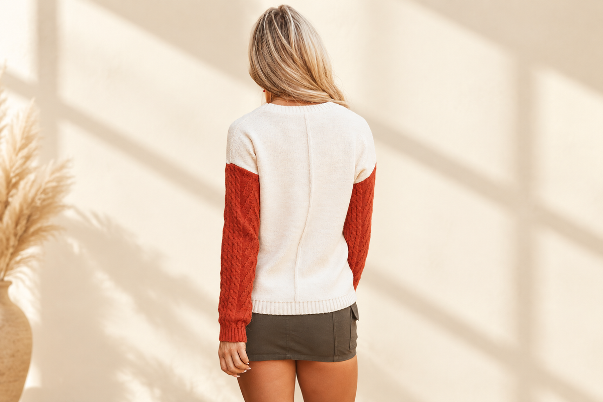 Rust and ivory colorblock patched-pocket drop shoulder sweater on a warm ivory boutique background, rust colorway angle 2